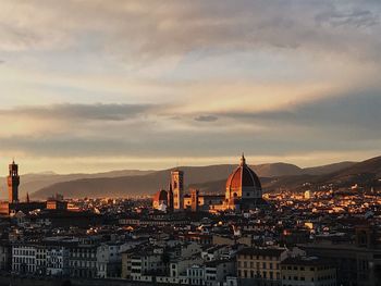 Illuminated buildings in city against sky during sunset