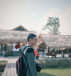 Side view of young man standing by field