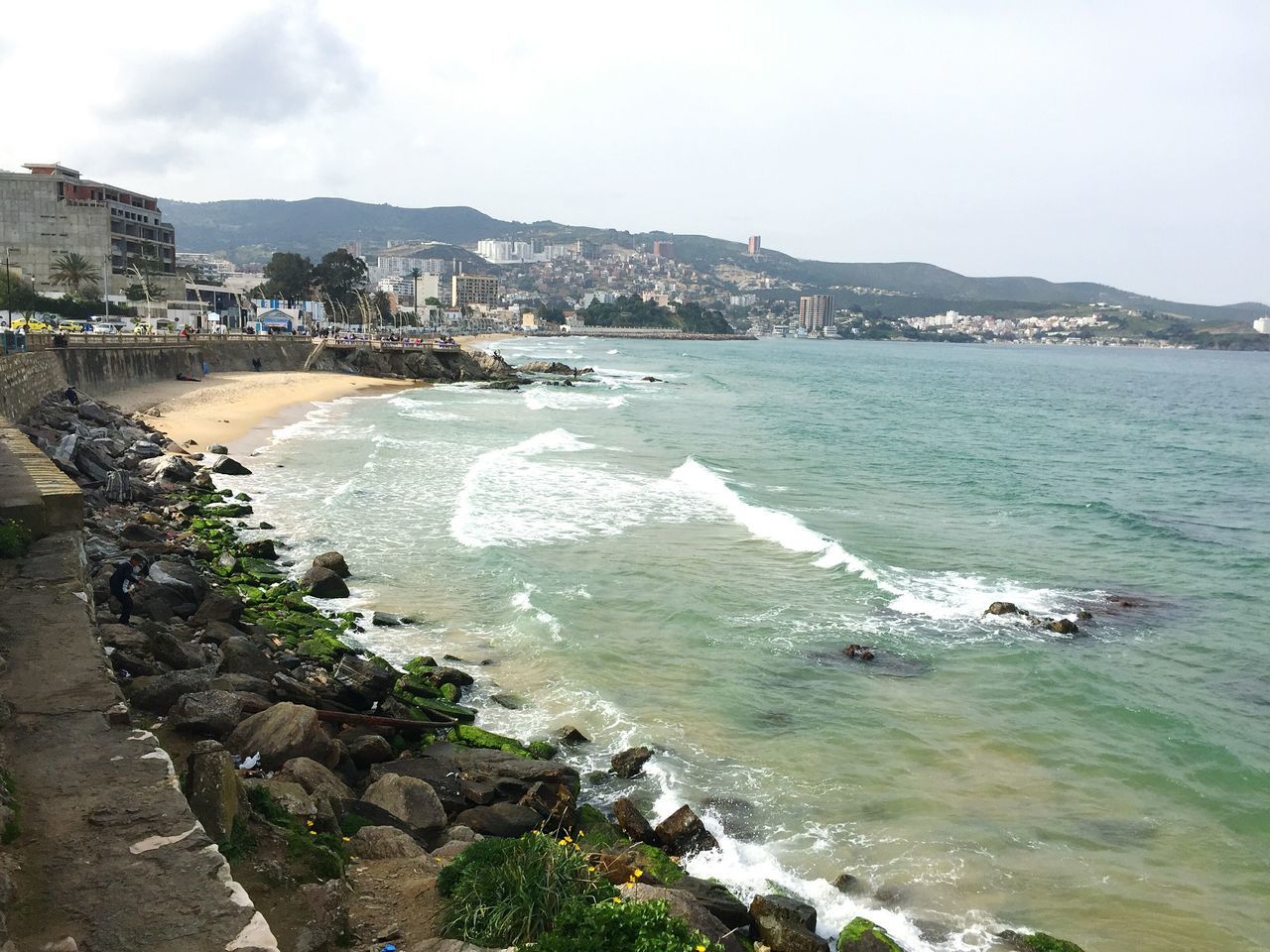 sea, water, beach, building exterior, coastline, shore, built structure, architecture, wave, sky, surf, horizon over water, high angle view, city, sand, scenics, nature, rock - object, beauty in nature, day