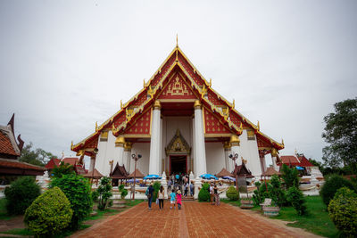 People at temple outside building against sky