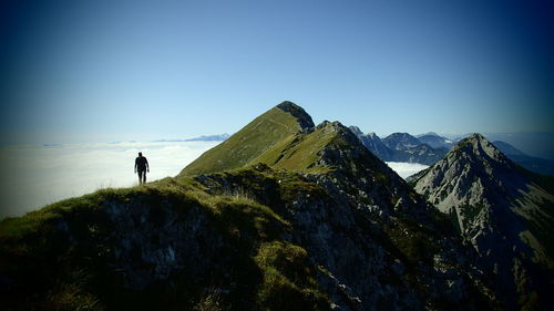 Man standing on mountain against clear blue sky