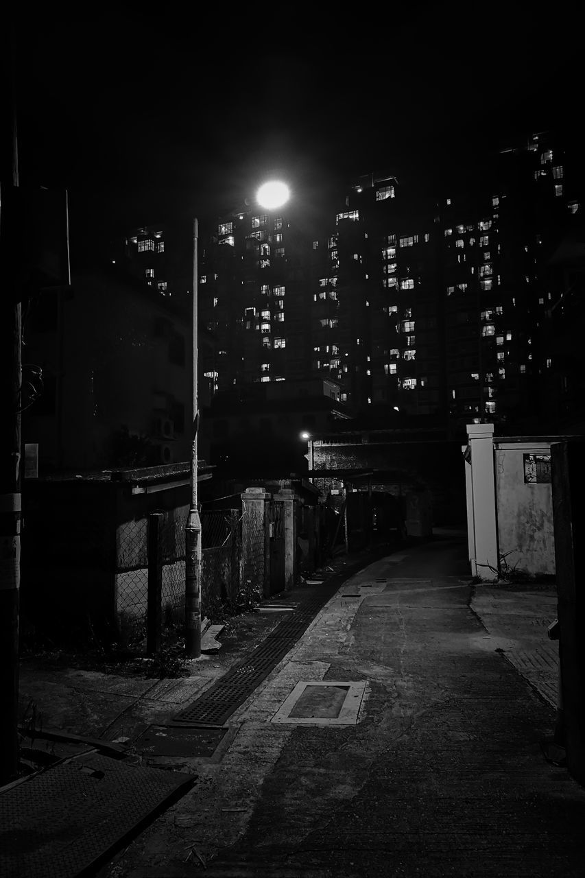 ILLUMINATED STREET BY BUILDINGS AGAINST SKY AT NIGHT