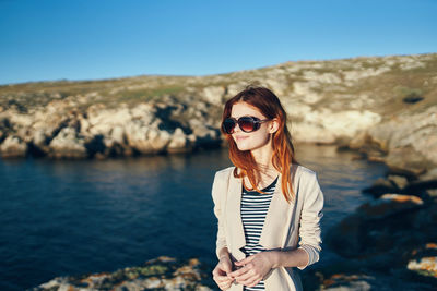 Portrait of woman wearing sunglasses standing against sky