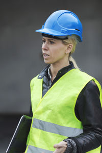 Female manual worker talking while holding laptop at factory