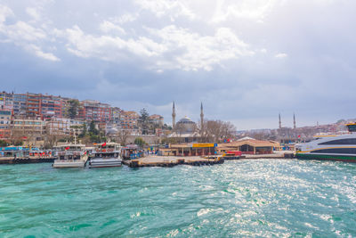 Boats in sea by buildings against sky in city