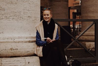 Portrait of smiling woman standing against wall