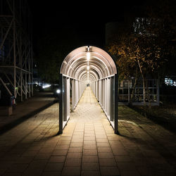 Illuminated footpath amidst buildings in city at night