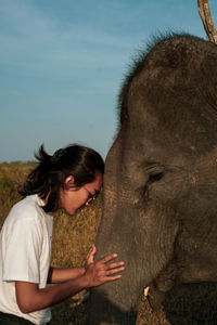 Side view of woman with elephant standing outdoors