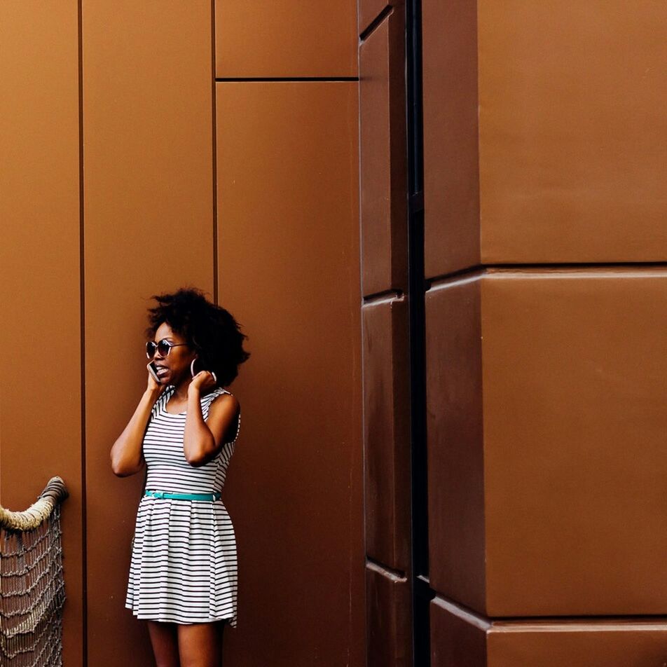 YOUNG WOMAN STANDING AGAINST WALL