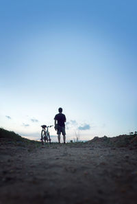 Rear view of men riding bicycle on road