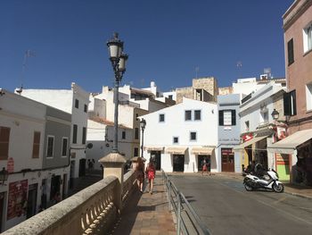 Street amidst buildings in city against clear blue sky