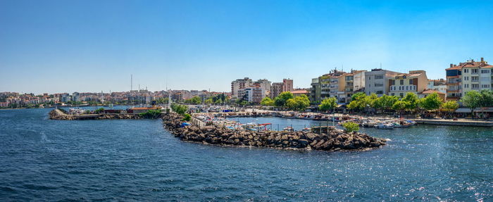 Sea by buildings against clear blue sky