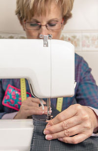 Woman sewing fabric over machine at home