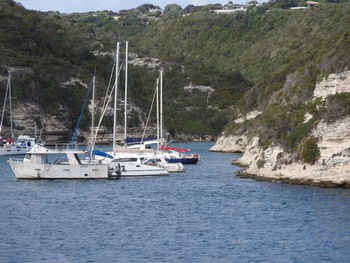 Sailboats moored on sea against mountain