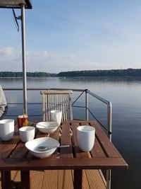 Crockery on table at lakeshore against sky