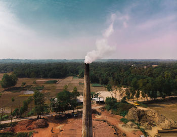 Smoke emitting from factory against sky