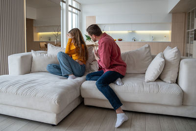 Side view of woman using digital tablet while sitting on sofa at home