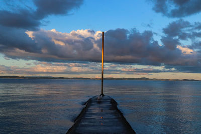 Pier over sea against sky during sunset