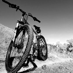 Bicycle parked on field against clear sky