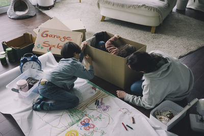 Mother with son drawing on cardboard box in living room at home