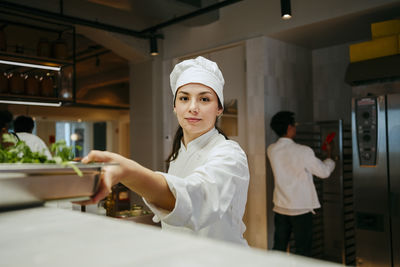 Portrait of young female chef working in commercial kitchen