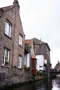 Houses by canal against sky