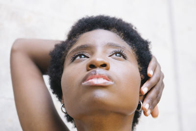 Cropped thoughtful young black lady with short dark afro hair touching face looking up