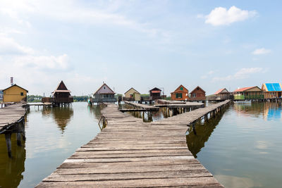 Pier amidst lake and houses against sky