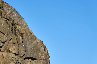 Low angle view of rock formation against clear blue sky