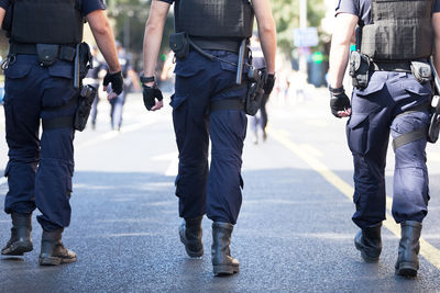 Low section of police men walking on street in city