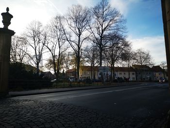 Street by buildings in town against sky