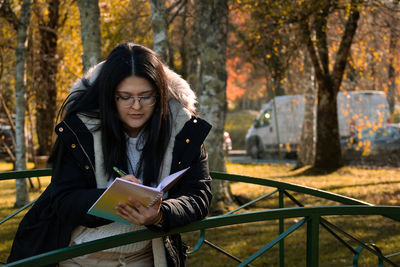 Young woman sitting in park during autumn