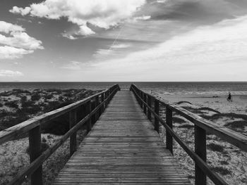 Pier on sea against cloudy sky