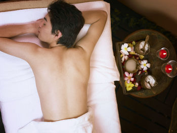 High angle view of shirtless young man sleeping on bed