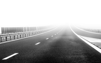 Empty road along bridge against clear sky