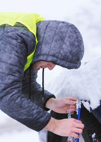 Side view of young man repairing snow covered car