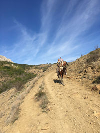 People riding horse on mountain against sky