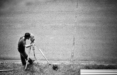 High angle view of man using theodolite on footpath