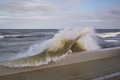 Sea waves splashing on shore against sky