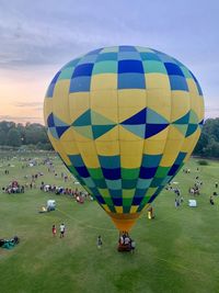 Hot air balloon around people against sky during sunset