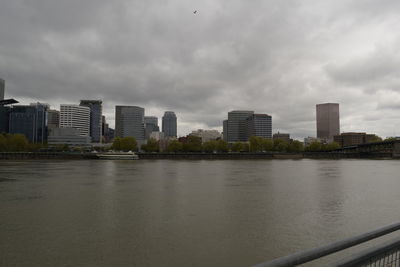 Buildings by river against sky in city