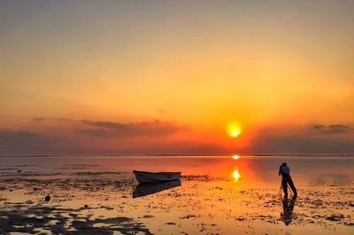 Rear view of man photographing sea at sunset