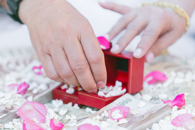 Cropped hand of man removing engagement ring from box on table