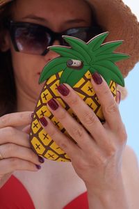 Close-up of woman holding mobile phone with pineapple shape cover