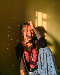 Smiling young woman sitting against wall