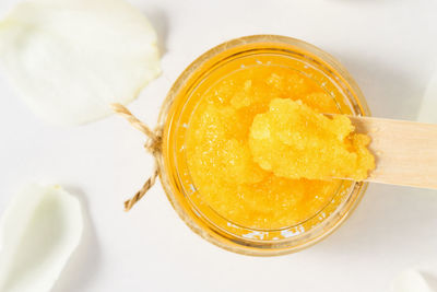 Homemade orange scrub in a glass container top view. body care, skin cleanser close-up.