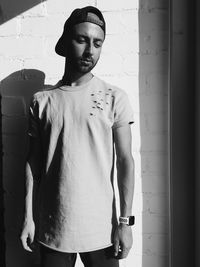 Portrait of young man standing against wall