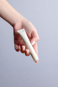 Cropped hand of woman holding medicine against blue background