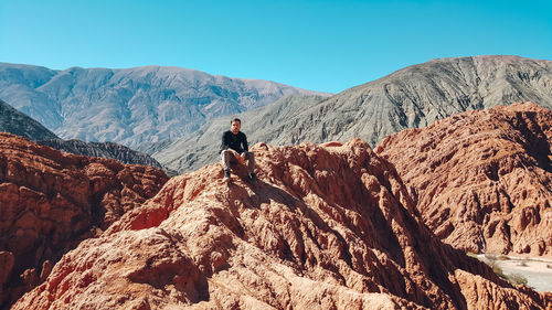 Full length of man on rock in mountains against sky