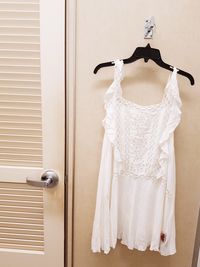 White dress hanging against wall at home